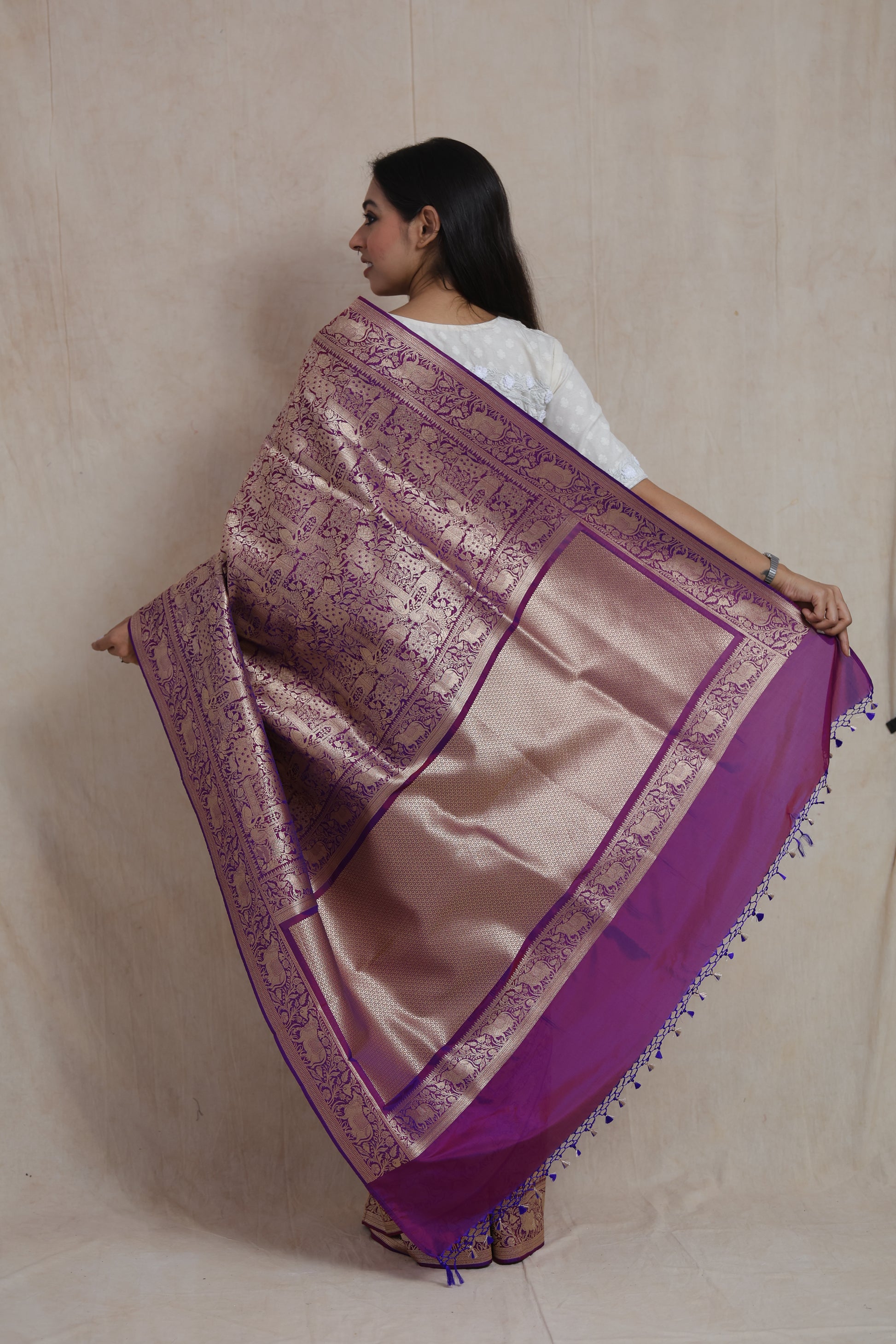 Back view showcasing luxurious woven pallu and zari detailing on royal purple silk saree.