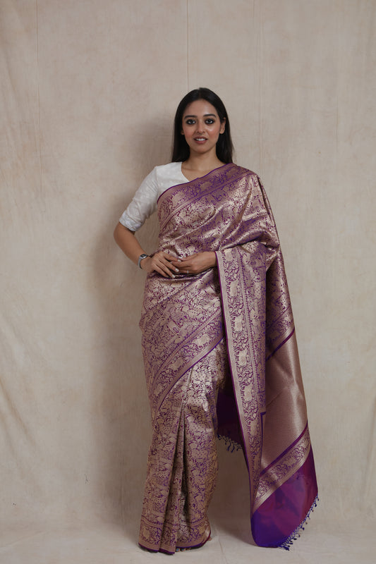 Model wearing royal purple Banarasi silk saree with intricate antique gold zari weaving.