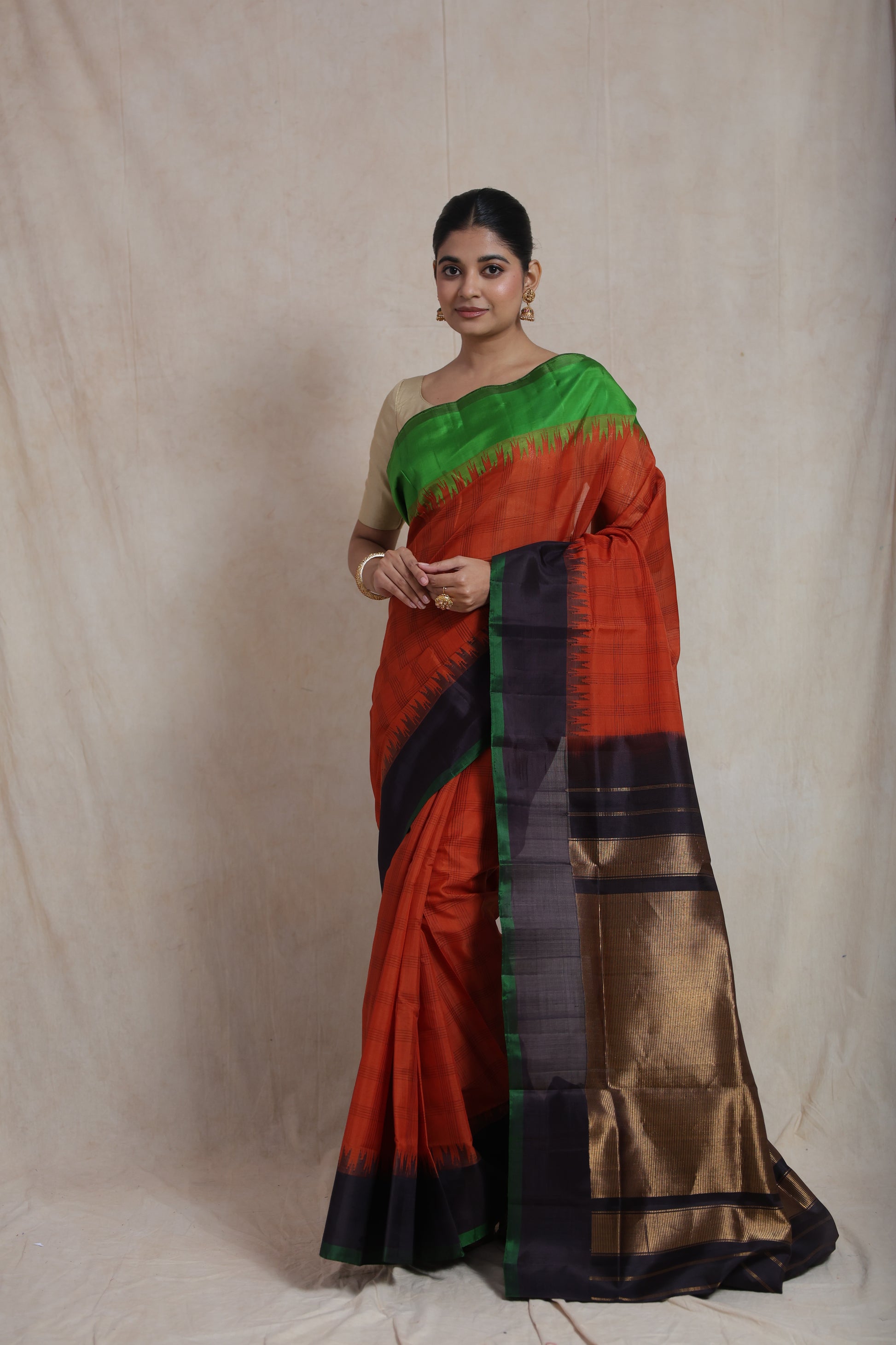Full view of model wearing rust orange Gadwal Sico saree with green border
