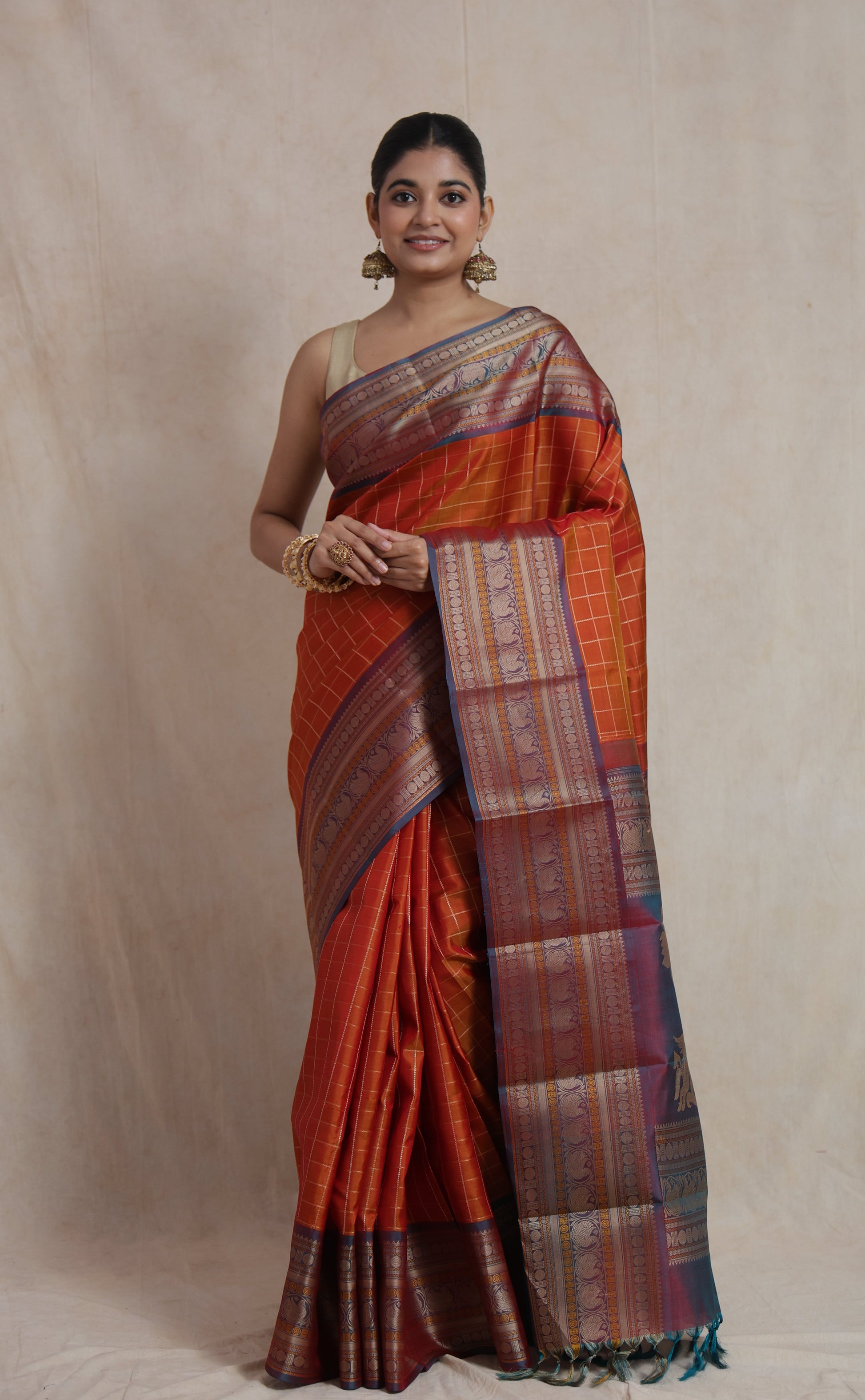 Front view of rust orange Kanjivaram silk saree with zari woven border