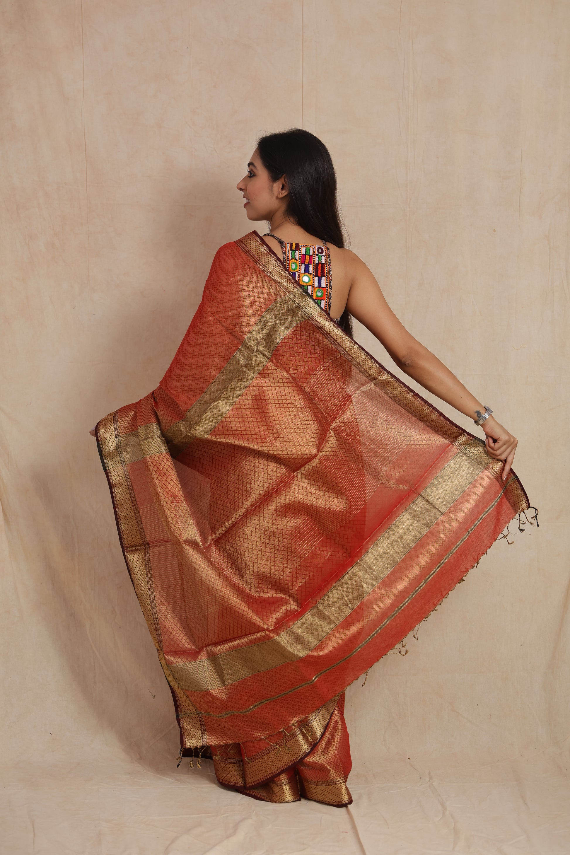 Back pallu display of rust orange Maheshwari tissue saree