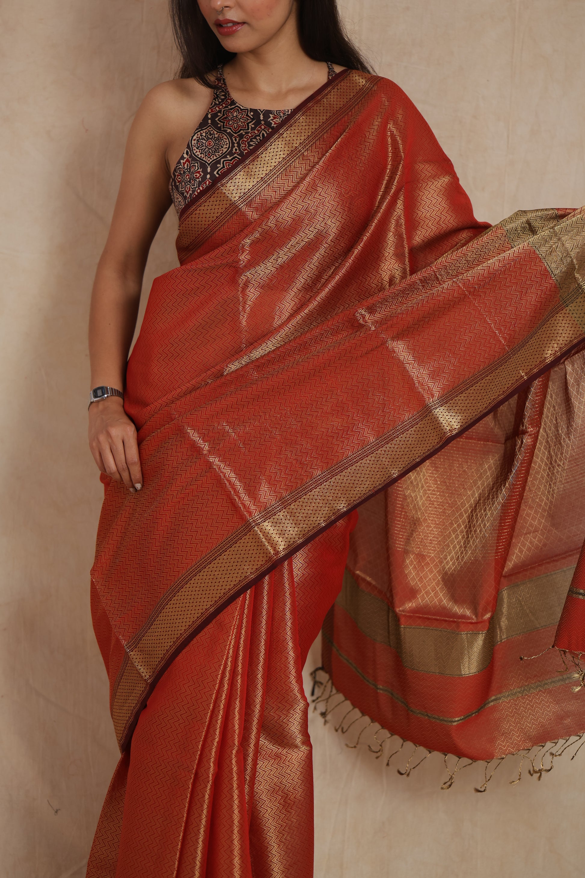 Close-up drape of rust orange Maheshwari tissue saree with zari weaving