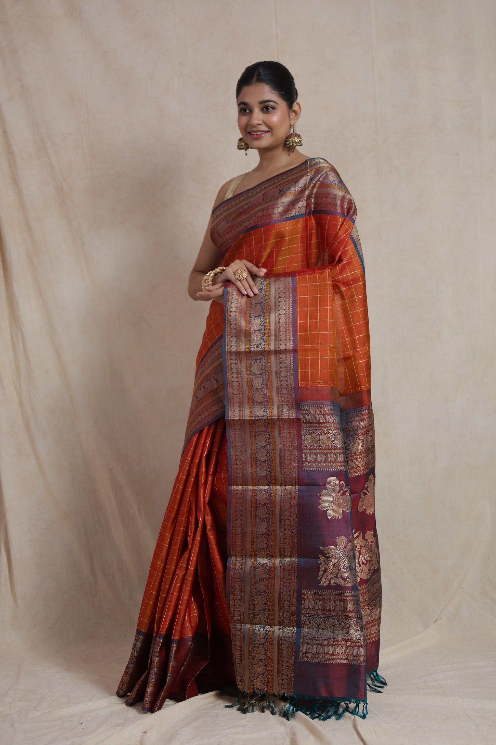 Side pose of rust orange Kanjivaram silk saree with woven zari pallu
