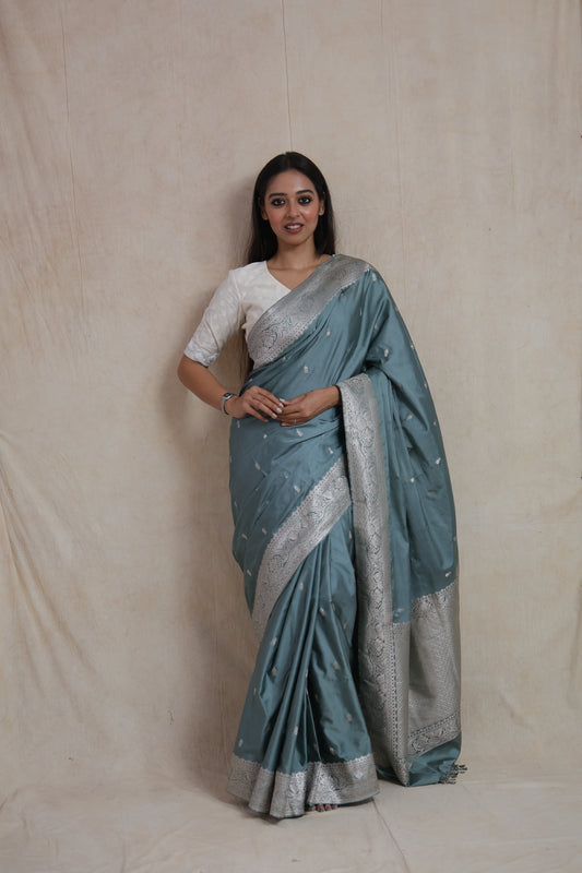Model wearing steel blue Banarasi silk saree with silver zari floral border front view
