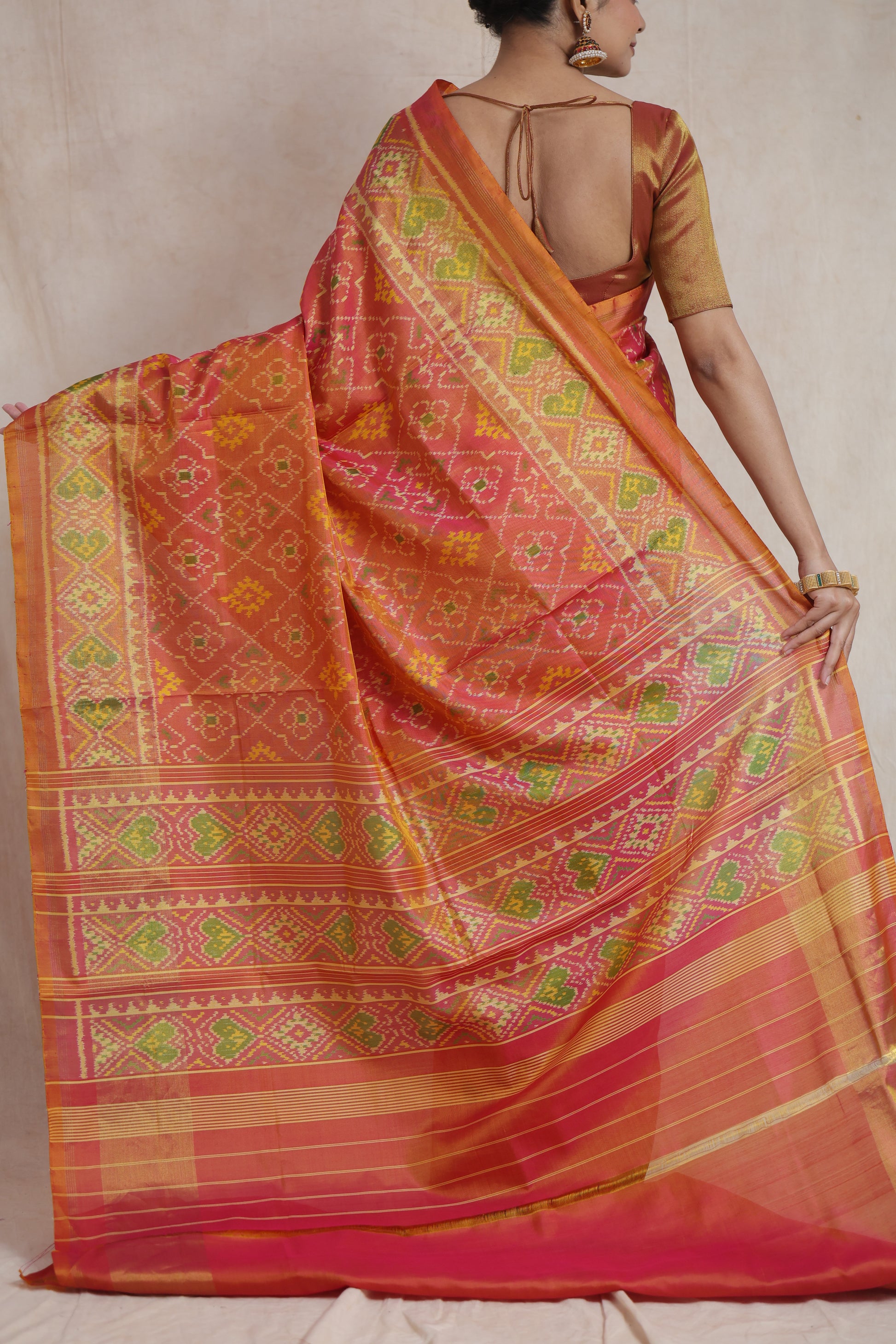 Back view of sunset coral Patola handloom silk saree with traditional woven pallu and ikat motifs