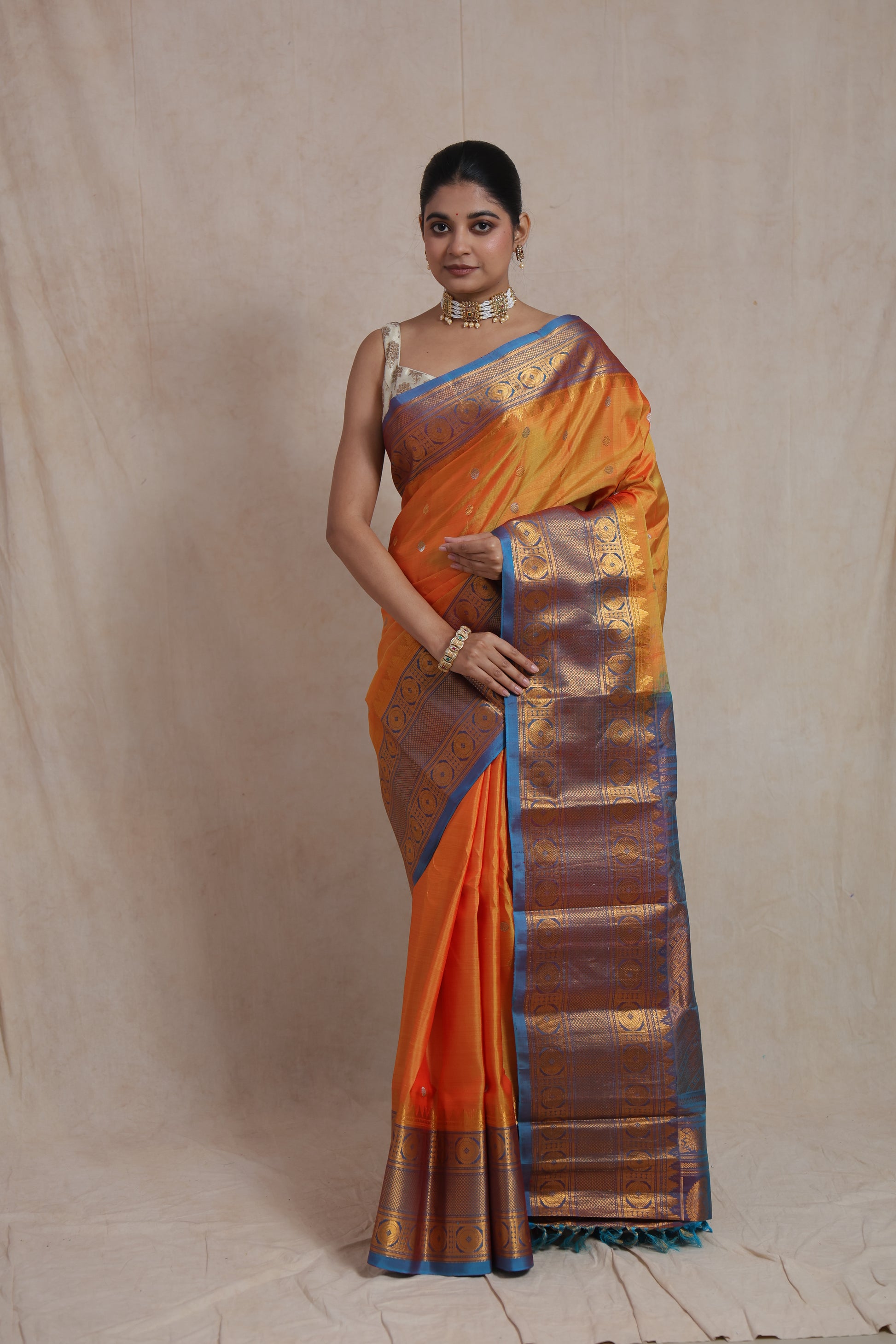 Front view of sunset orange Gadwal silk saree with royal blue zari border