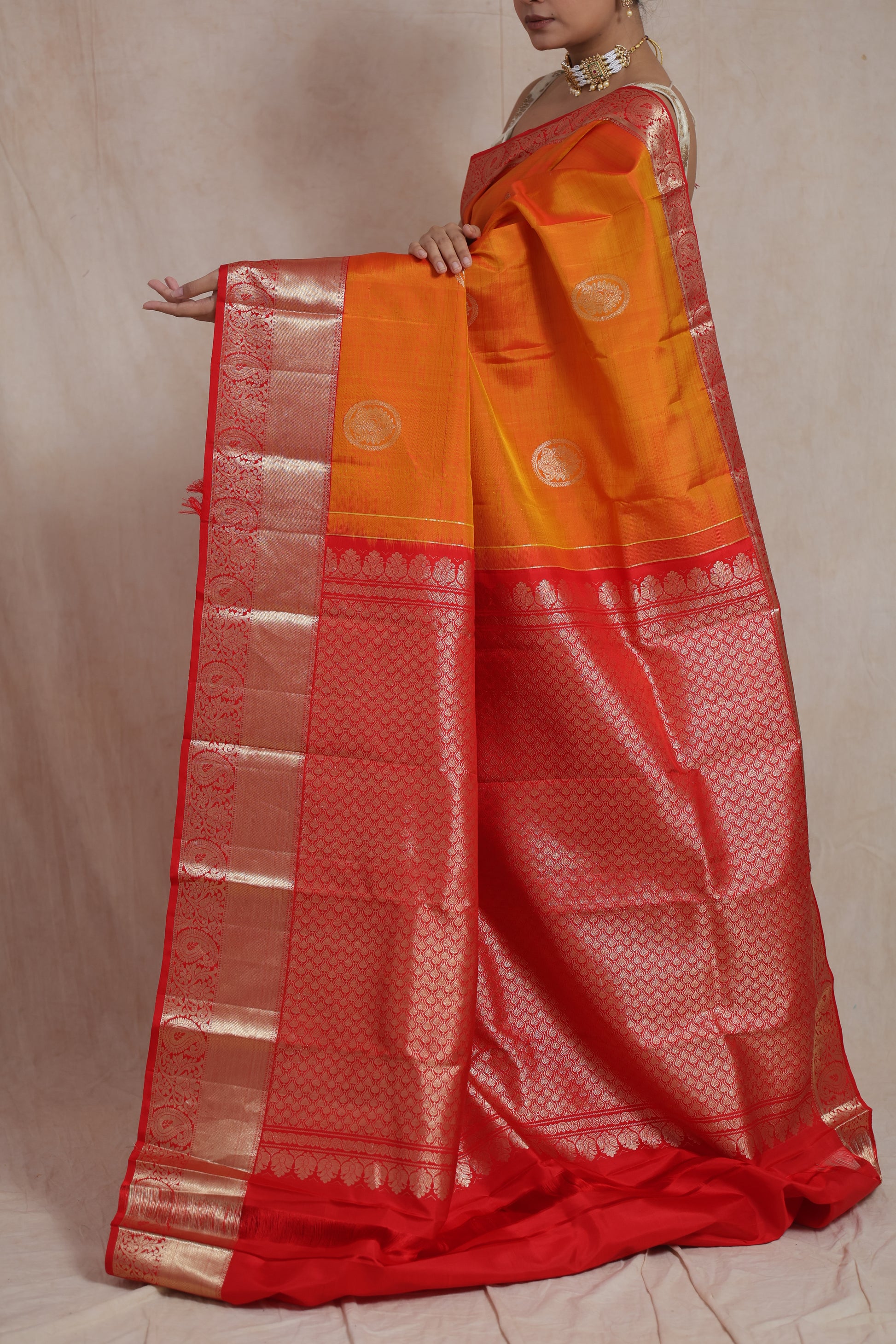Front pose of orange Kanjivaram silk saree with rich red zari border