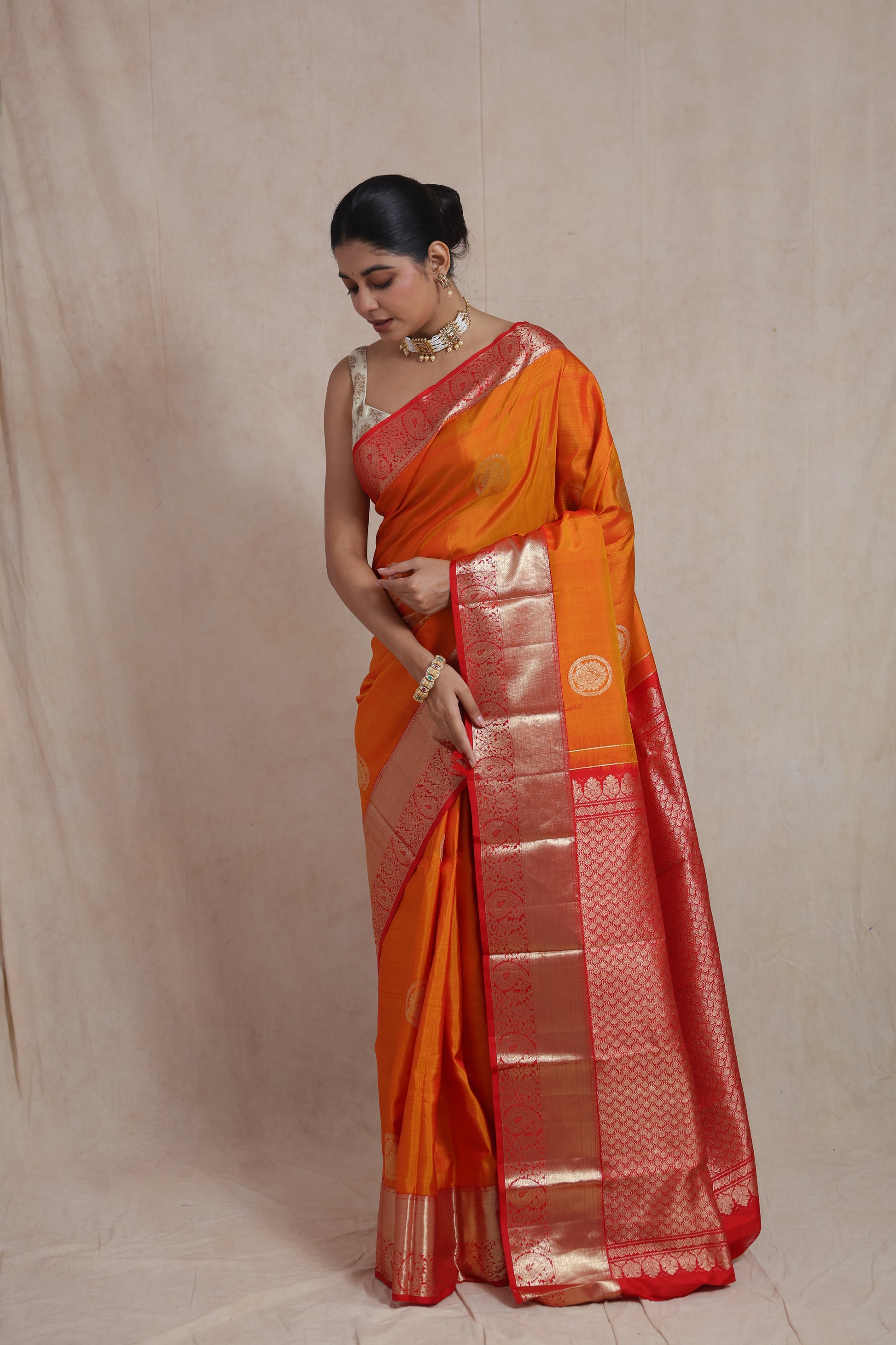 Portrait view of traditional orange Kanjivaram silk saree with golden zari work