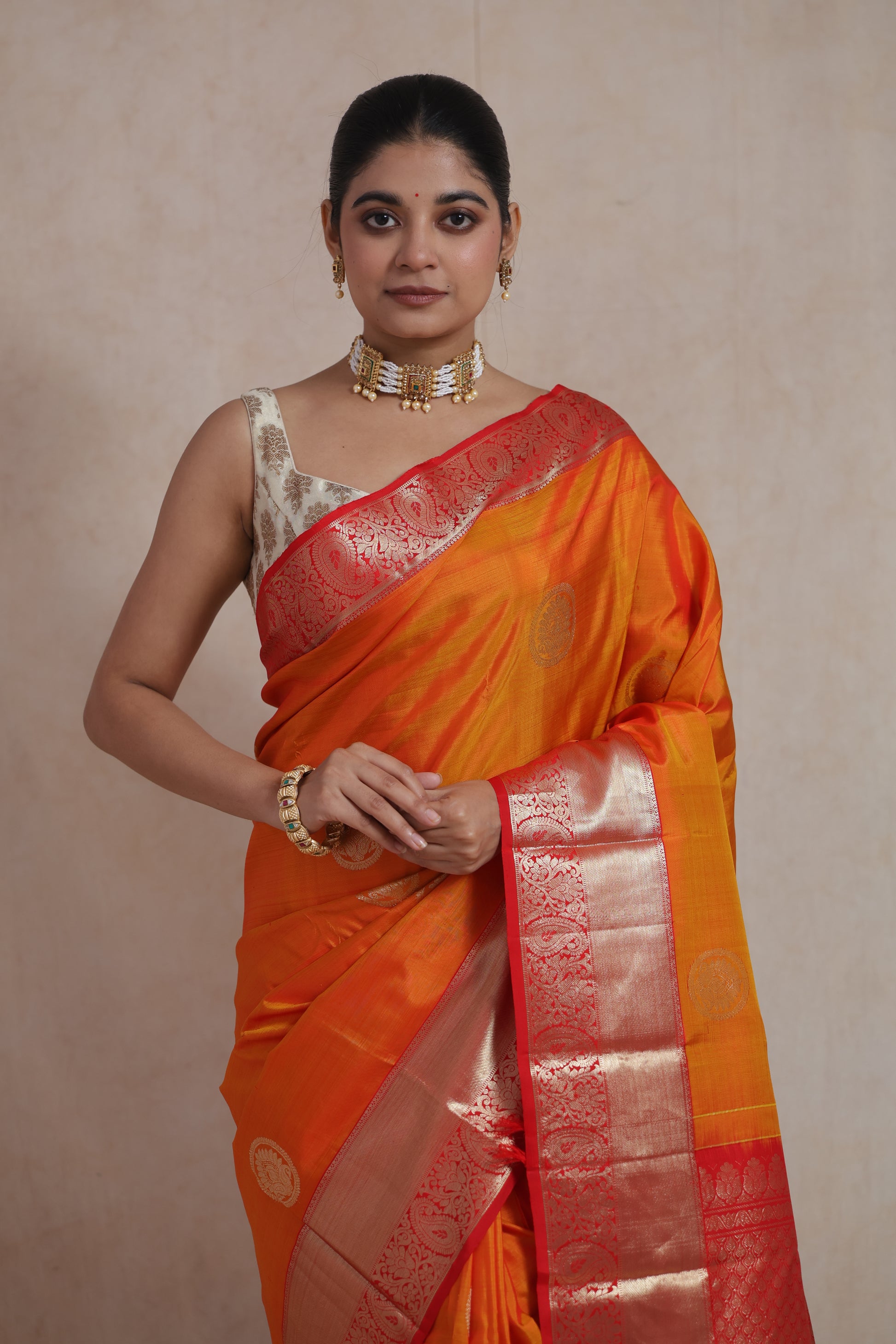 Elegant standing pose in orange Kanjivaram silk saree with zari motifs