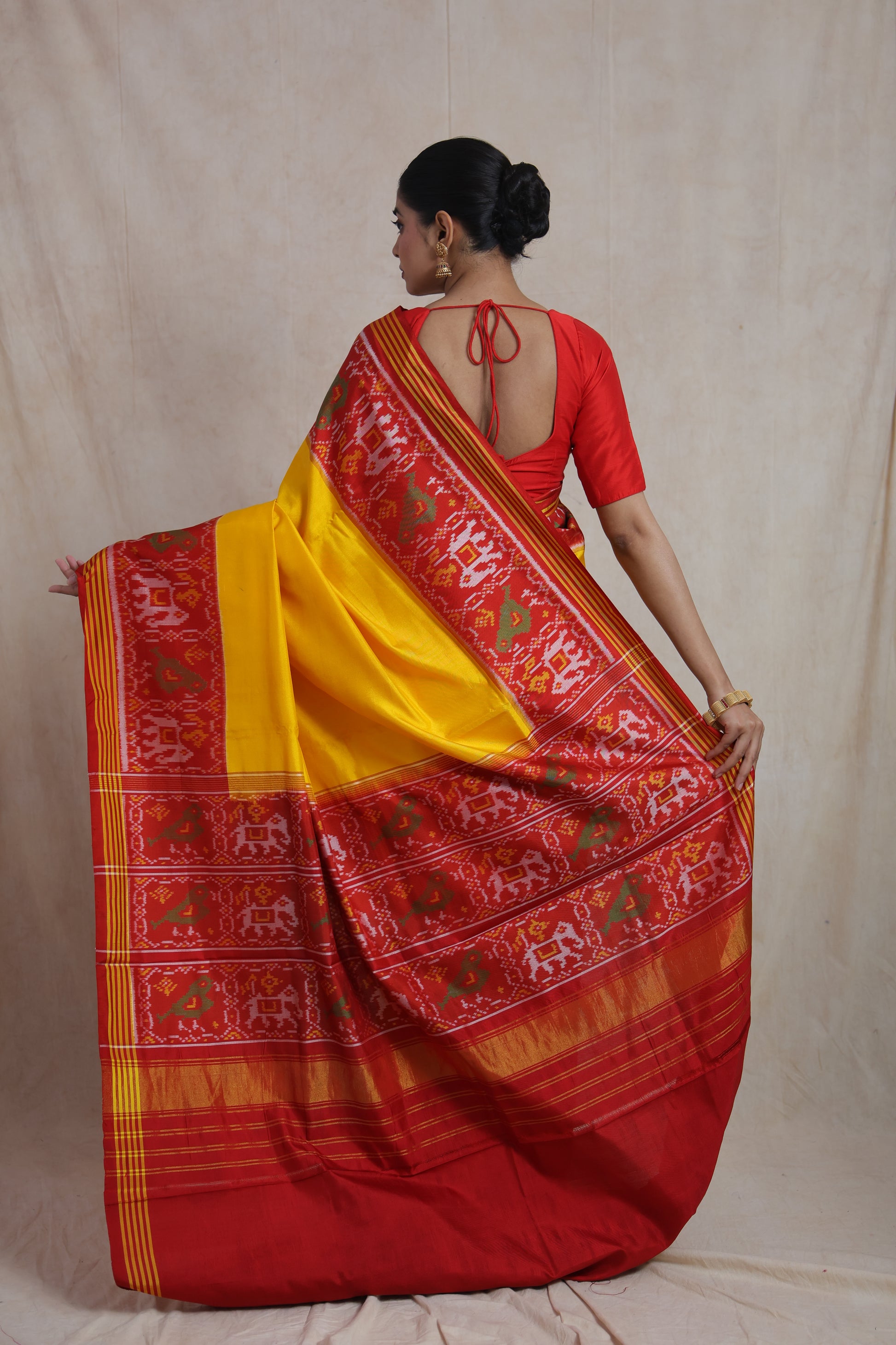 Back view of sunshine yellow Patola handloom silk saree with red ikat woven pallu and traditional motifs