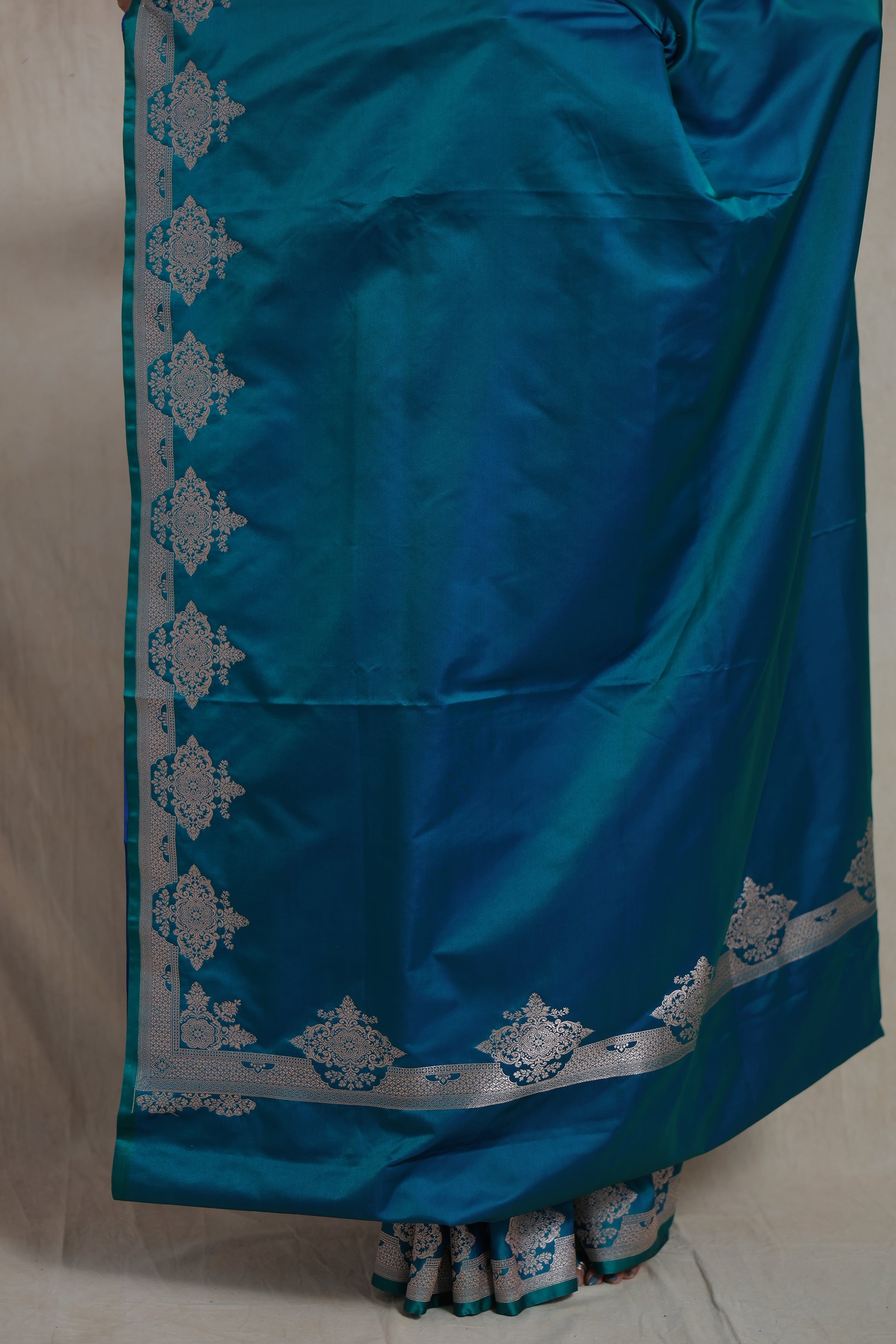 Closeup of silver zari floral border on teal blue Banarasi art silk saree
