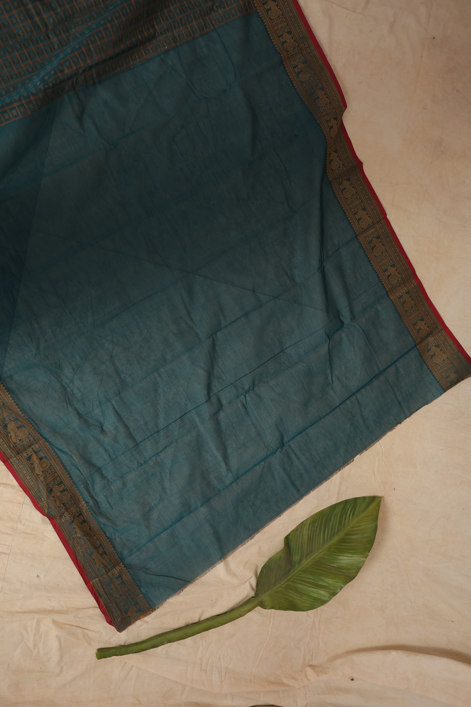 Detailed view of teal blue Kanchipuram cotton saree border with gold zari weaving