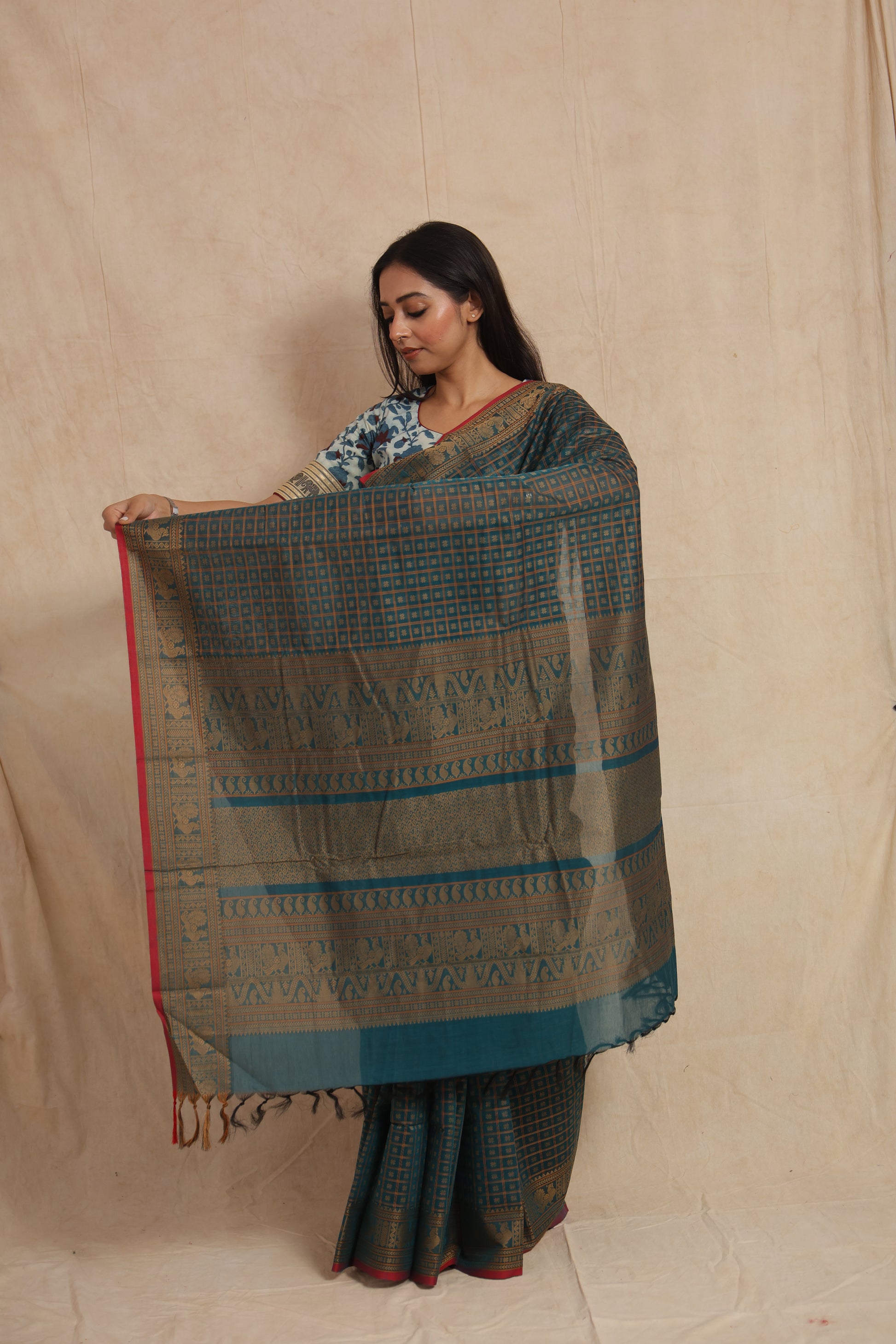 Model displaying detailed zari woven pallu of teal blue Kanchipuram cotton saree