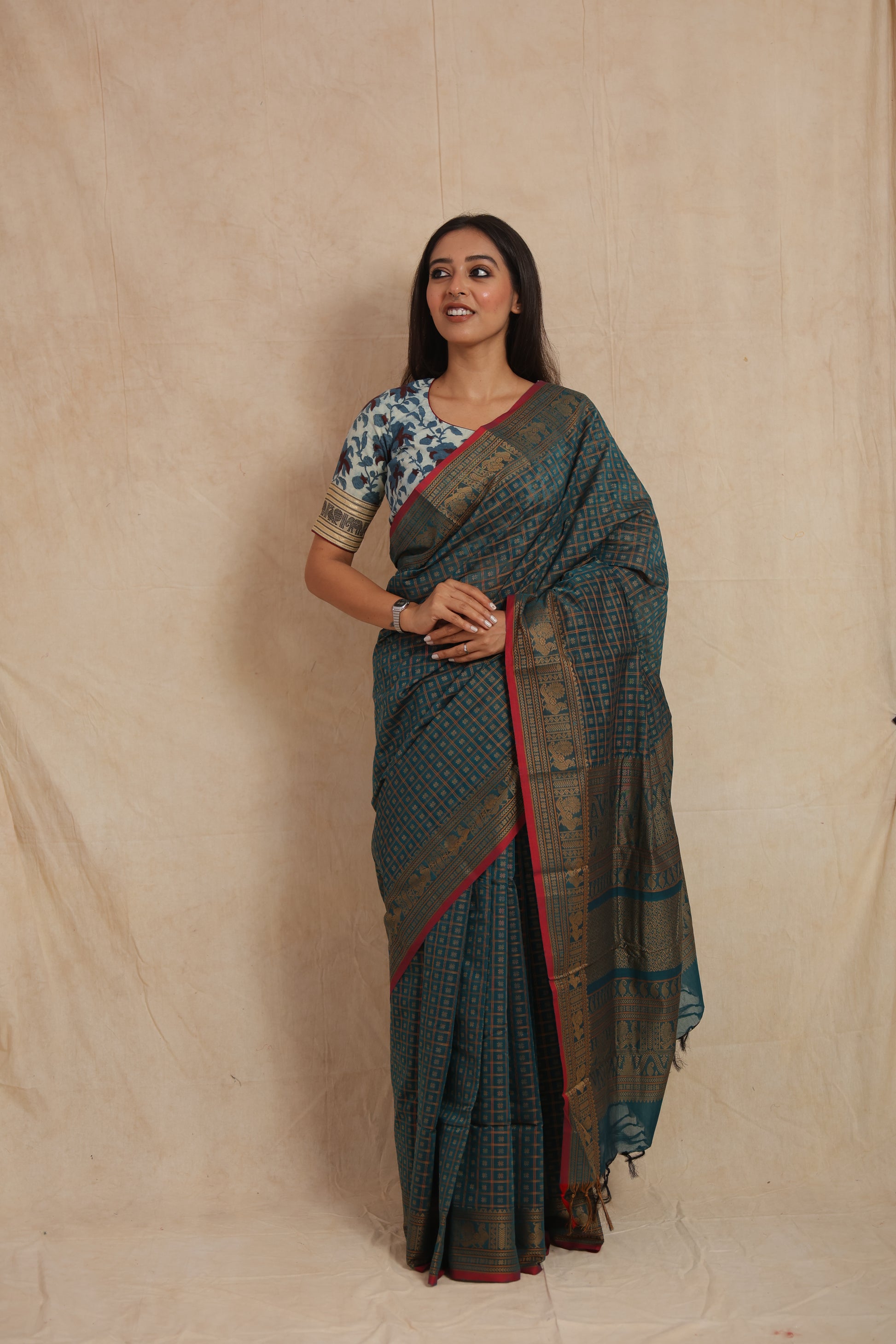 Woman posing in teal blue Kanchipuram cotton saree with traditional zari woven border
