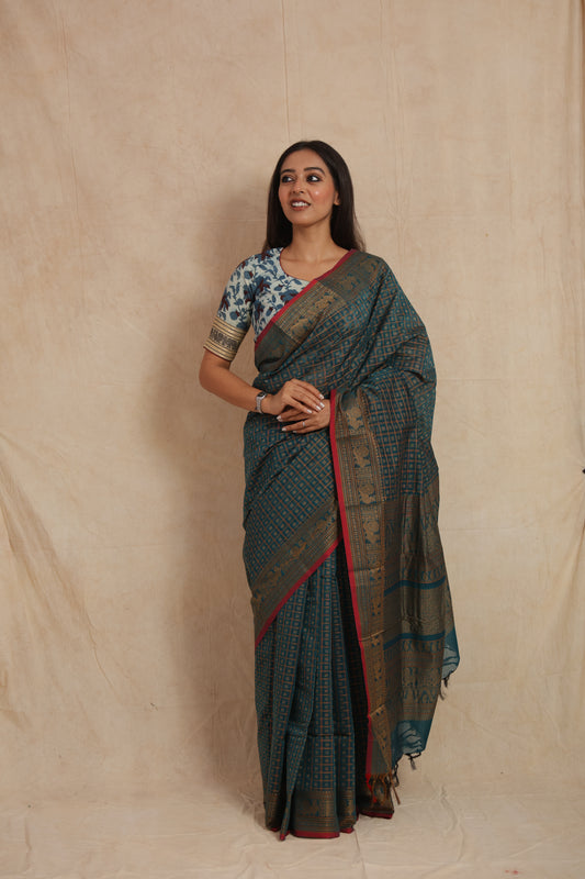 Woman posing in teal blue Kanchipuram cotton saree with traditional zari woven border