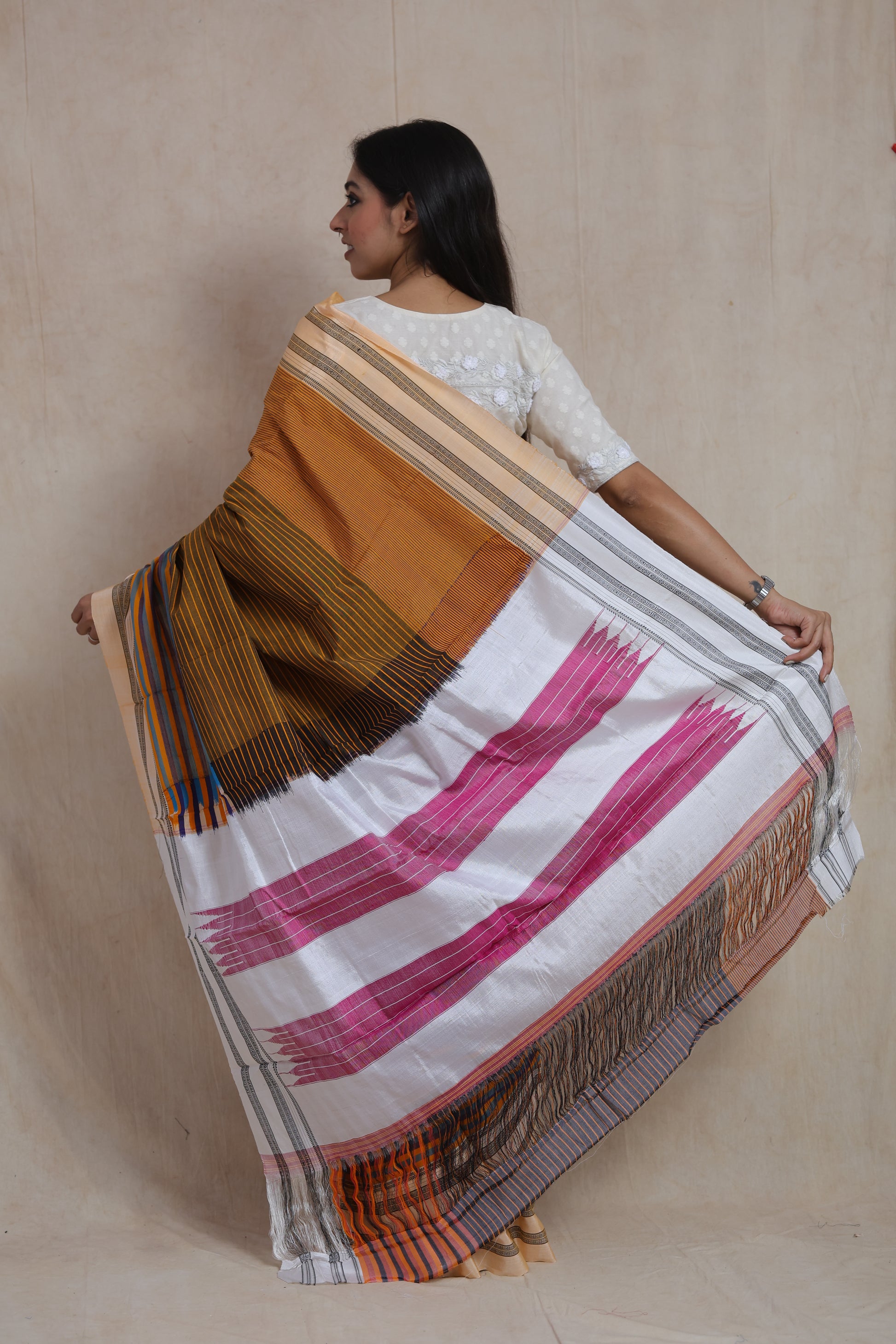 Back view of mustard brown Ilkal handloom cotton saree showcasing the distinctive white and pink pallu