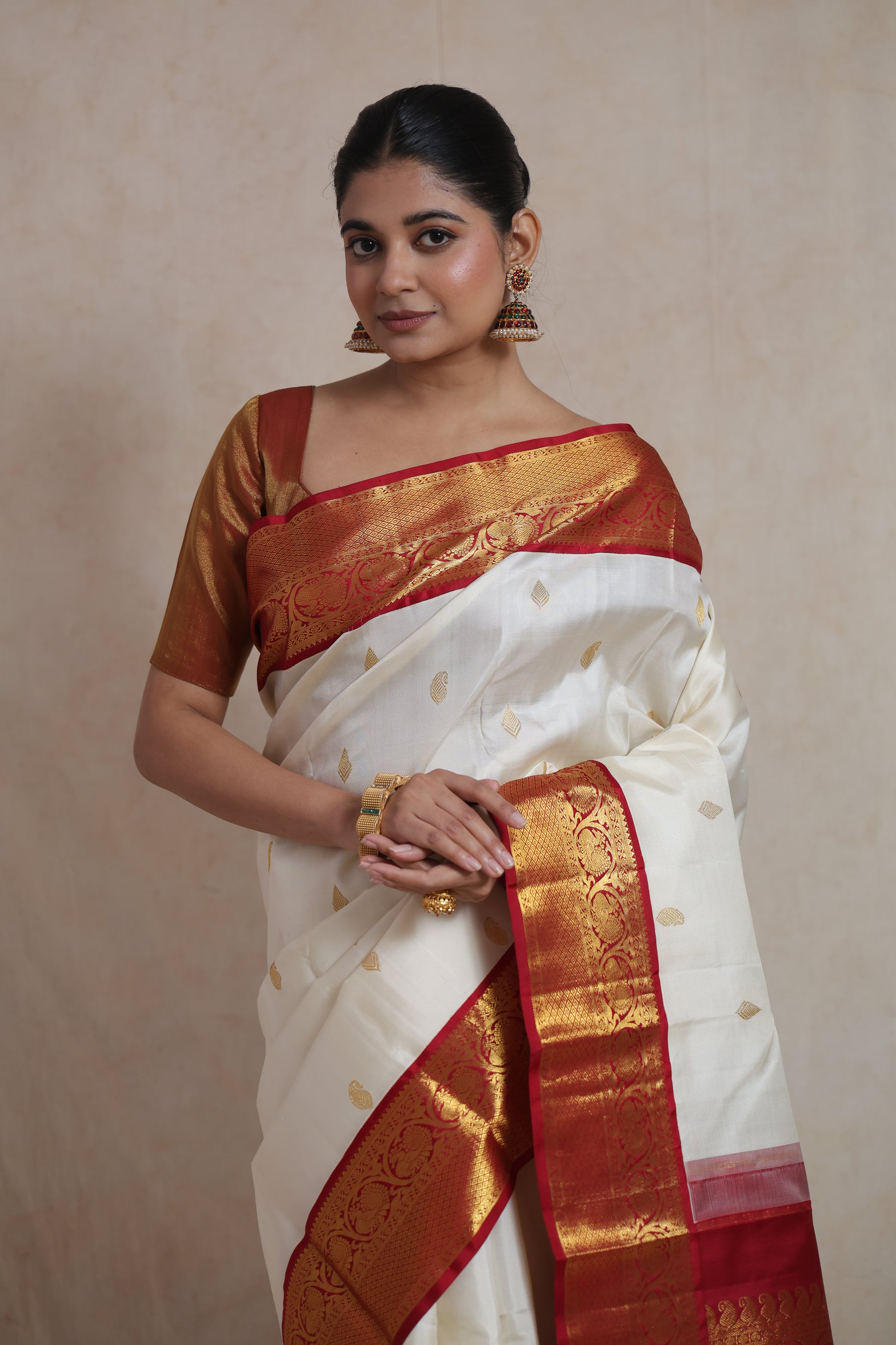 Portrait view of ivory white Kanjivaram pure silk saree featuring woven motifs and rich red border