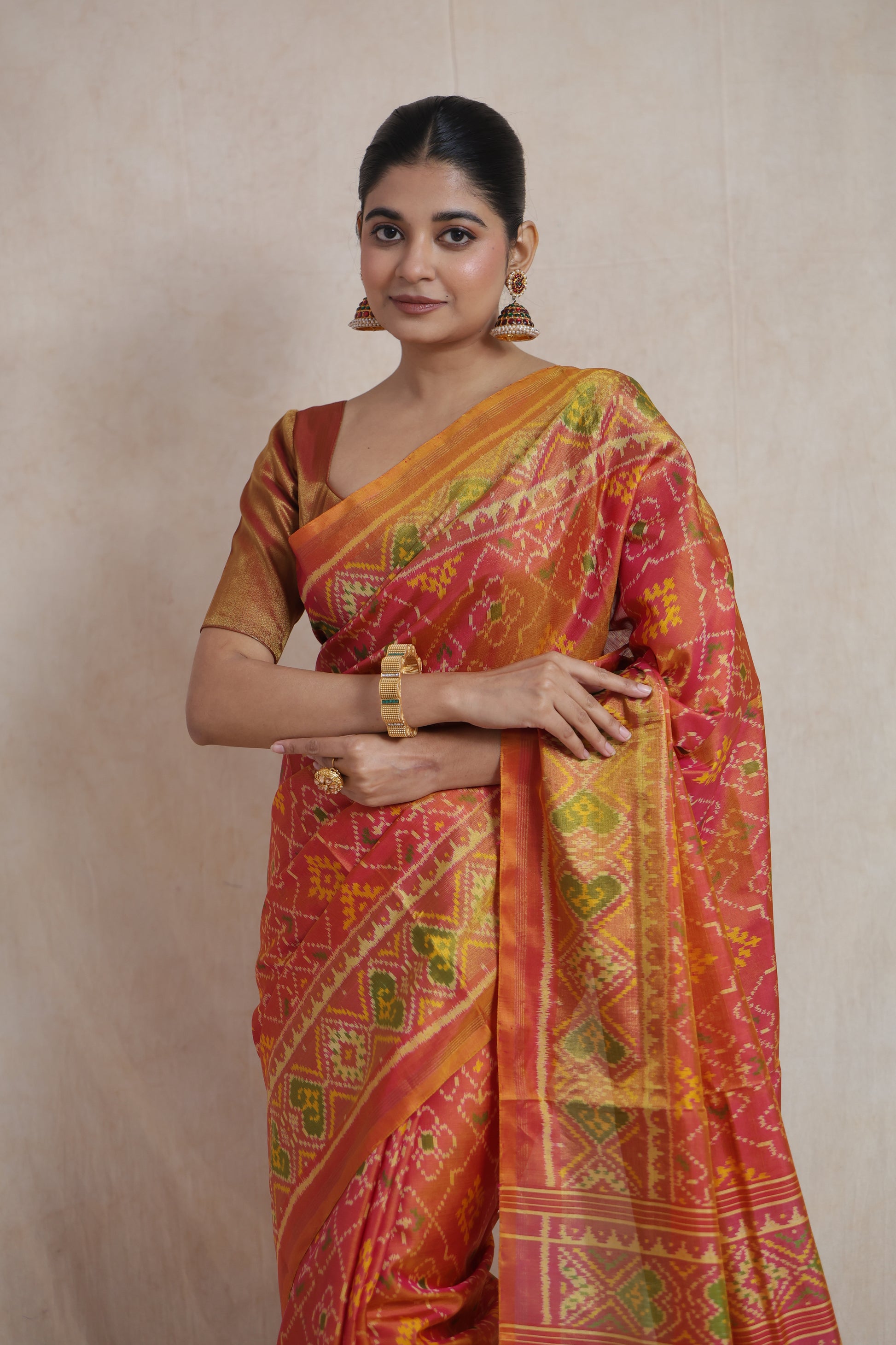 Portrait view of handwoven Patola silk saree in coral tones with intricate woven motifs
