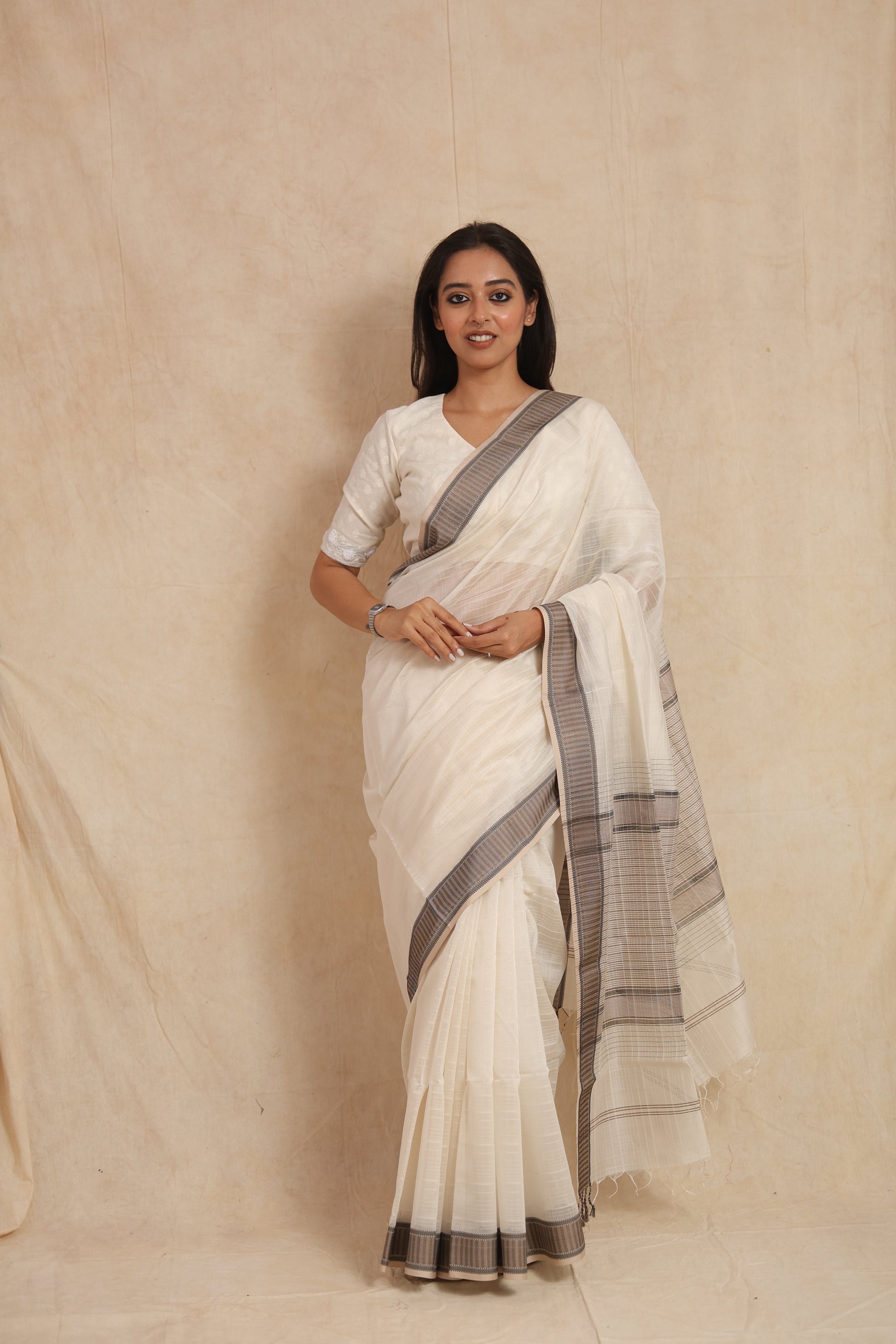 Full-length portrait of ivory Maheshwari silk tissue saree with striped pallu