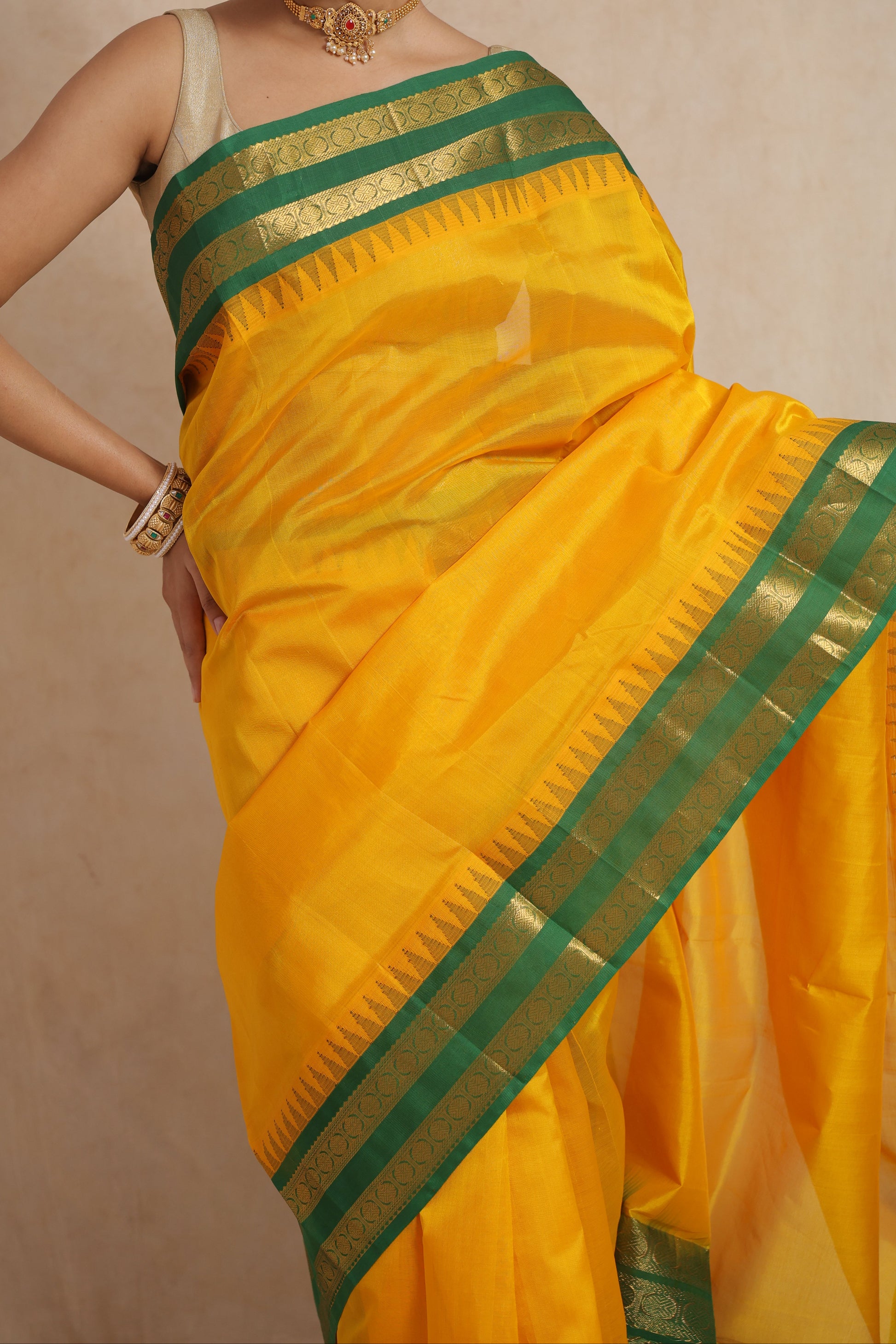 Close-up of golden yellow Kanchipuram Sico saree with emerald green zari border