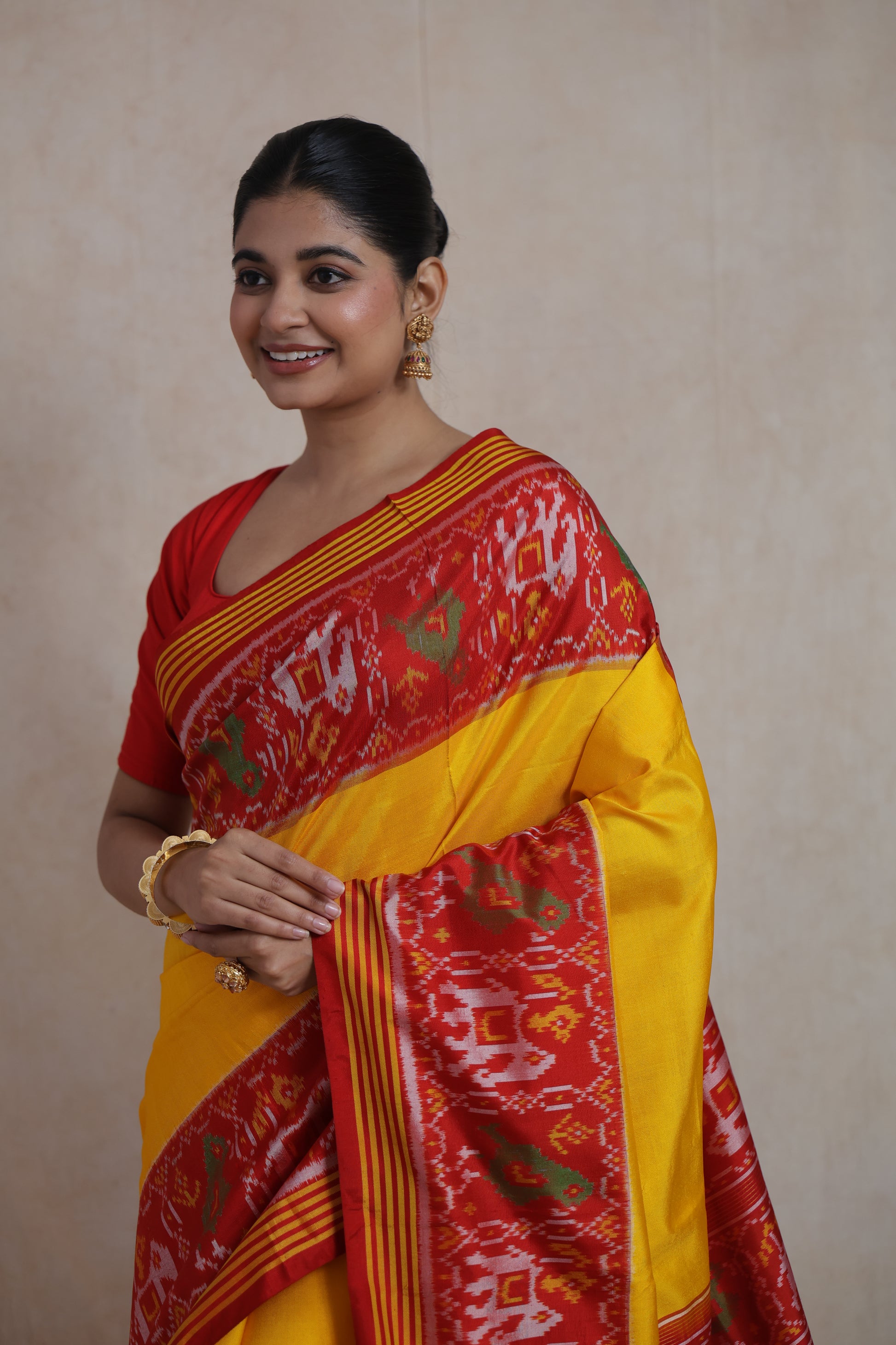 Elegant drape of sunshine yellow Patola silk saree with traditional red woven border and pallu